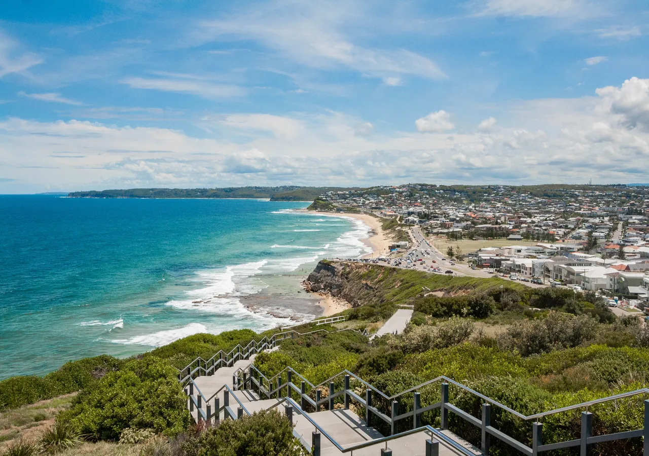 An aerial view of a coastal suburb curving around a bay.