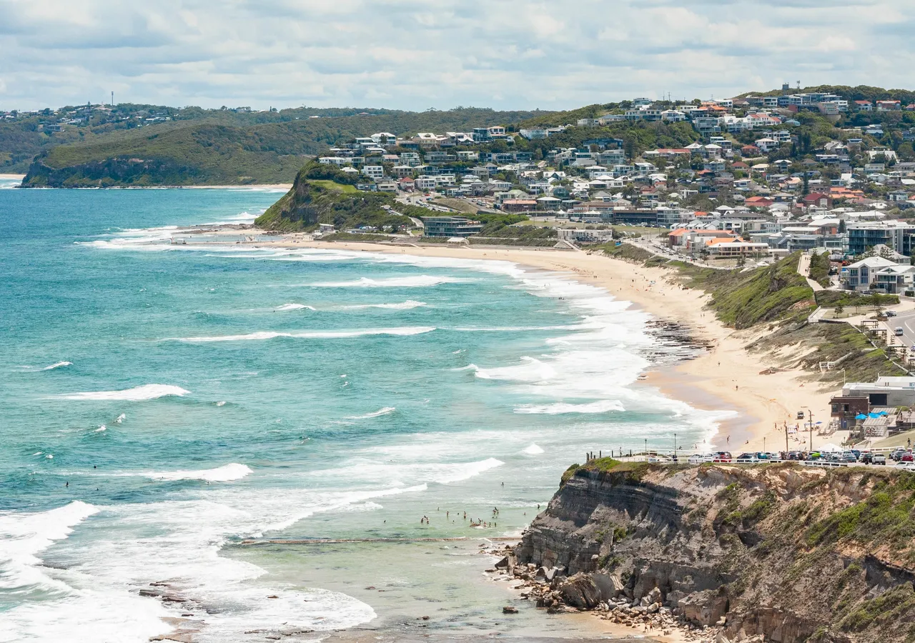 A coastal town spread along a headland above a surf beach.
