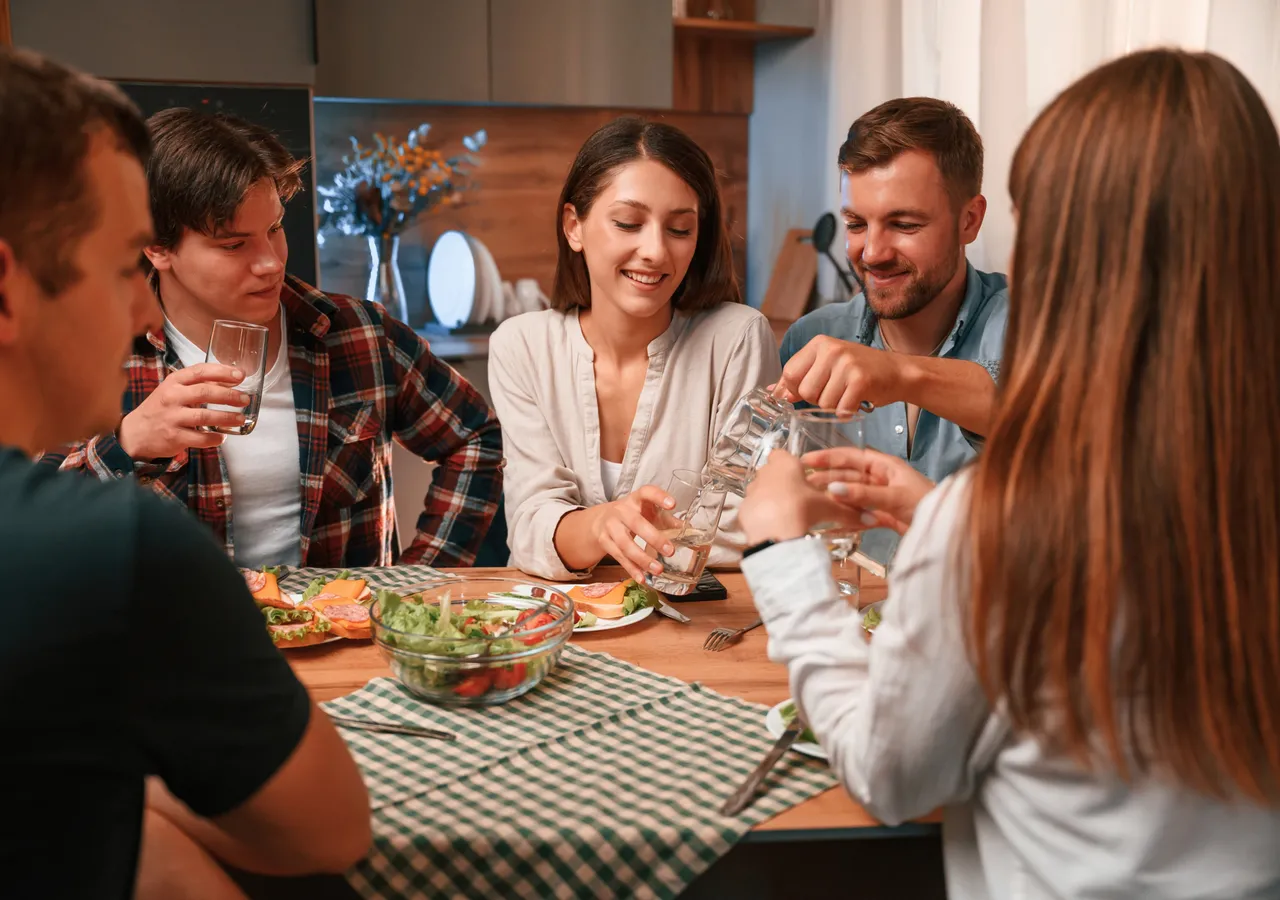 A group of friends seated around a dinner table, talking over a shared meal.