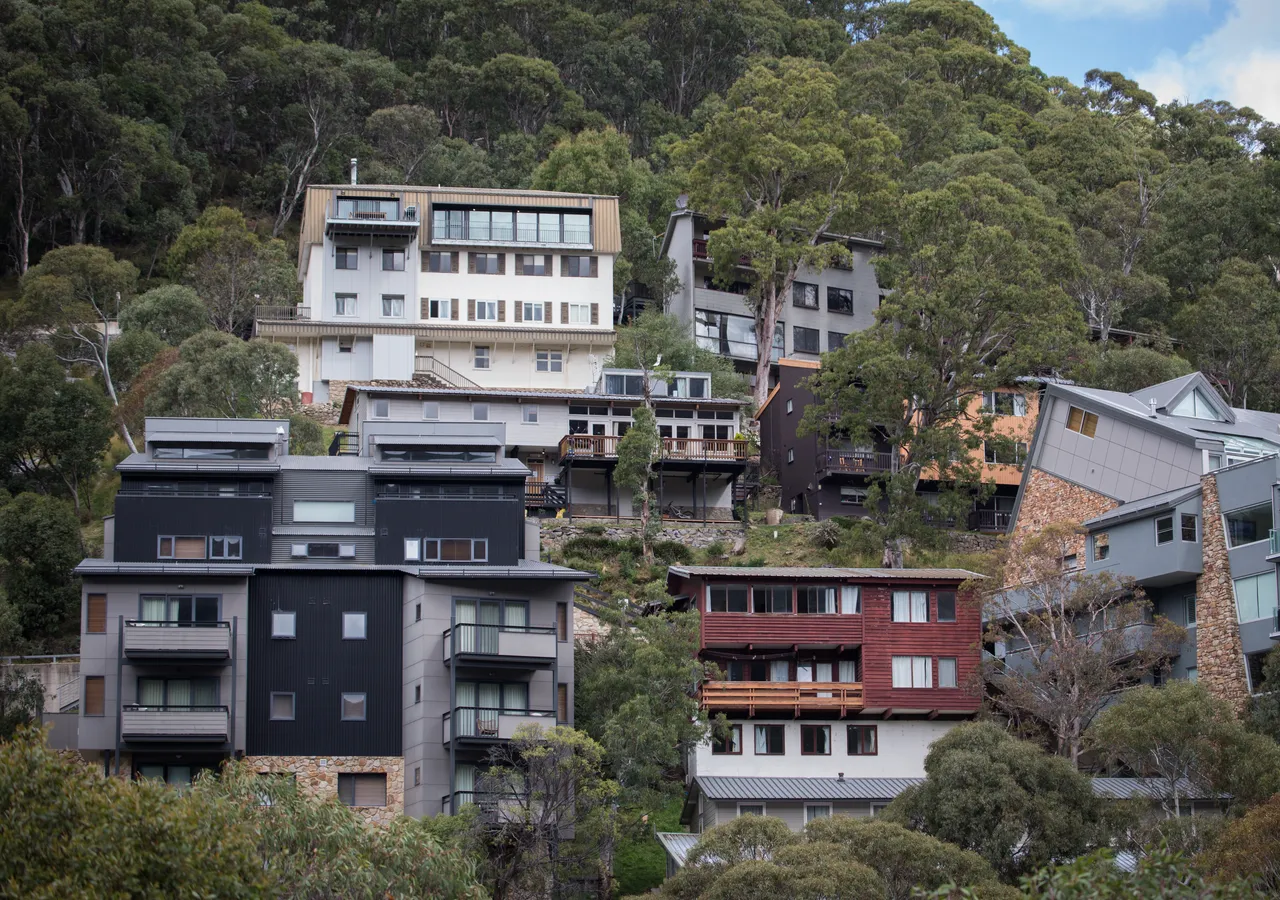 Terraced apartment buildings stepping down a wooded hillside.