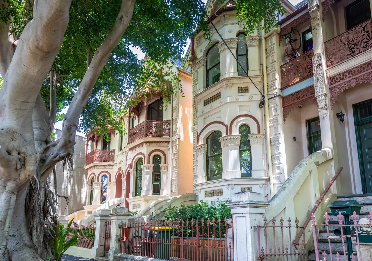 Ornate two-storey Melbourne terrace houses on a tree-lined street.