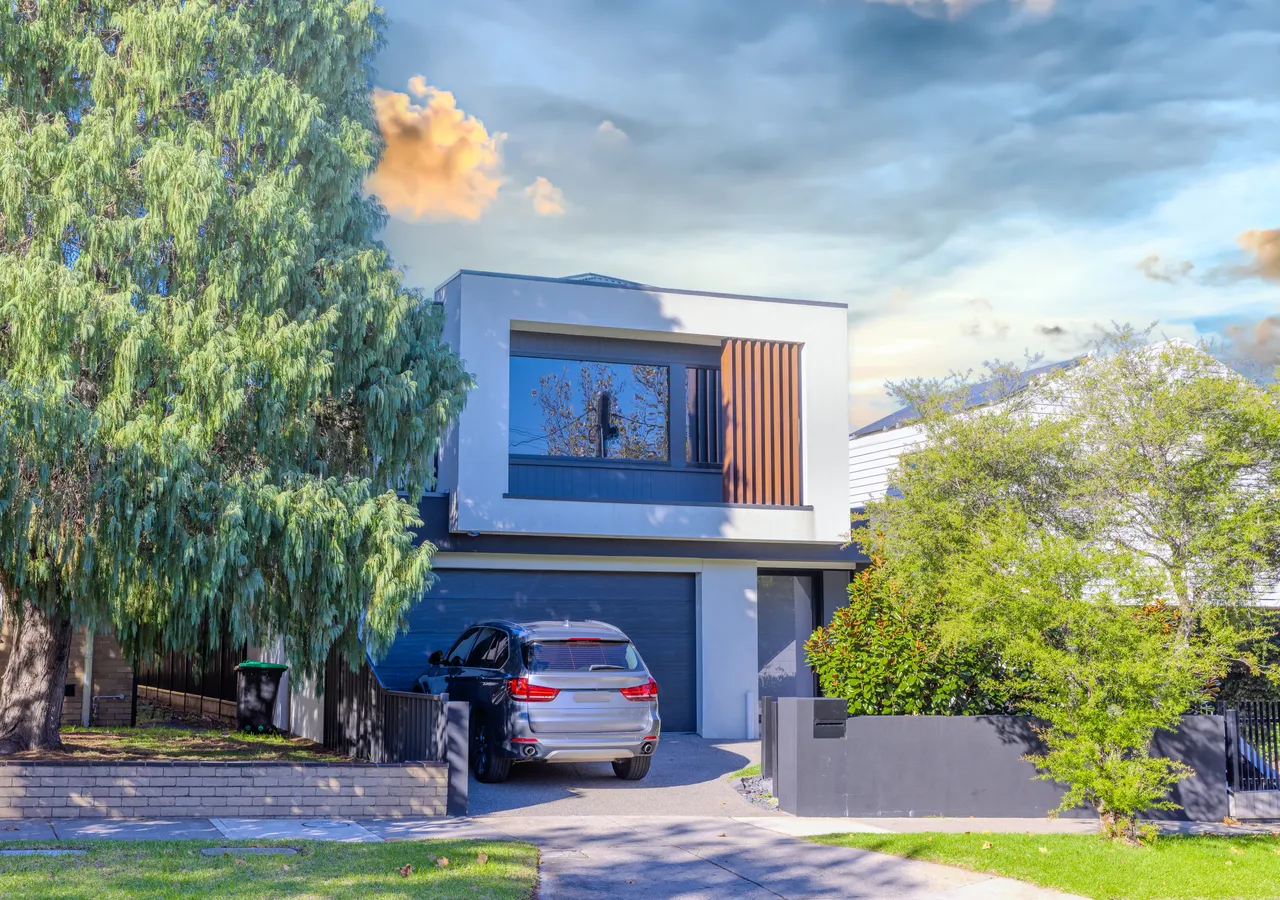 A contemporary two-storey house with a double garage, photographed at dusk.