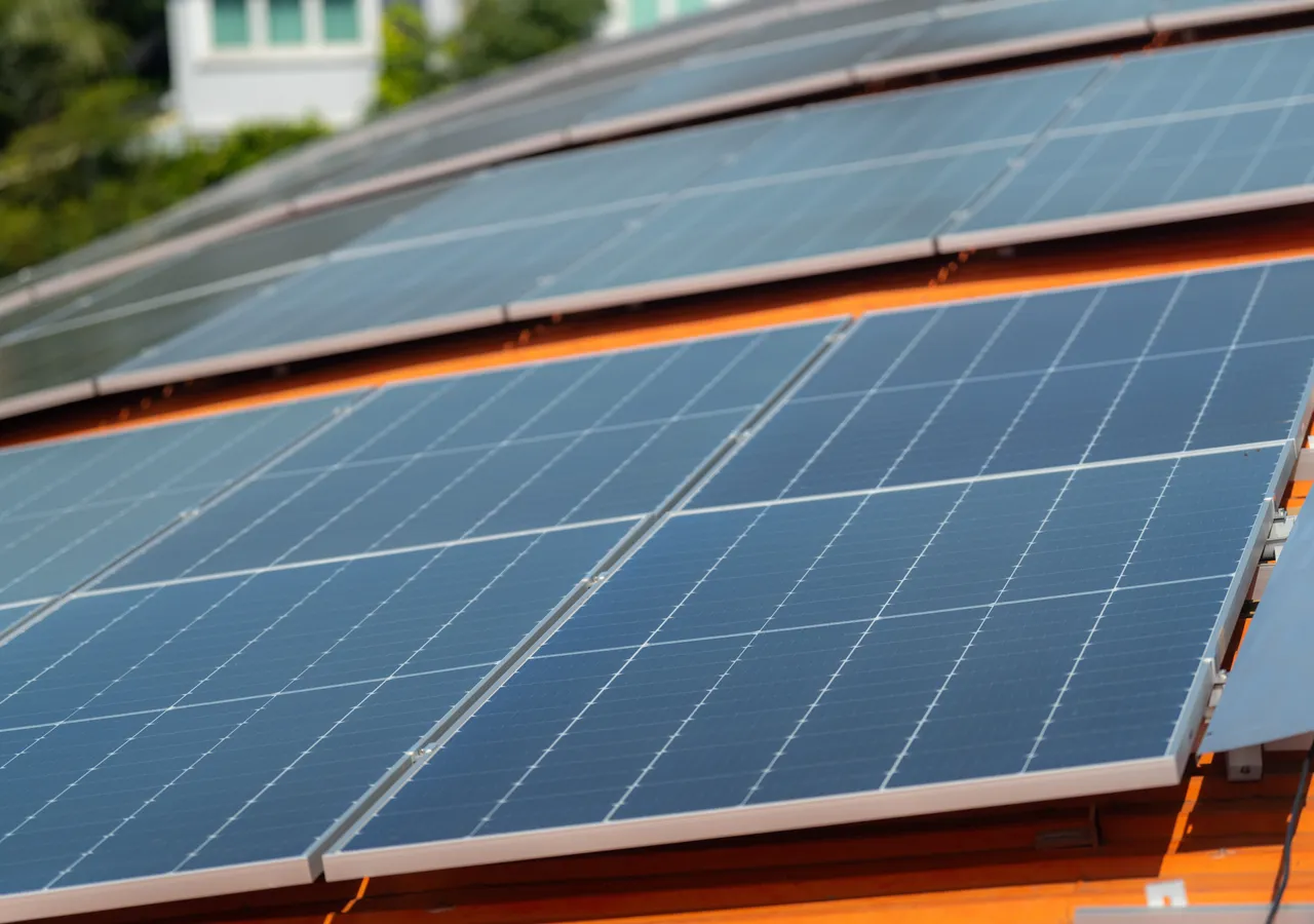 A close view along a row of solar panels mounted on the tiled roof of a house.