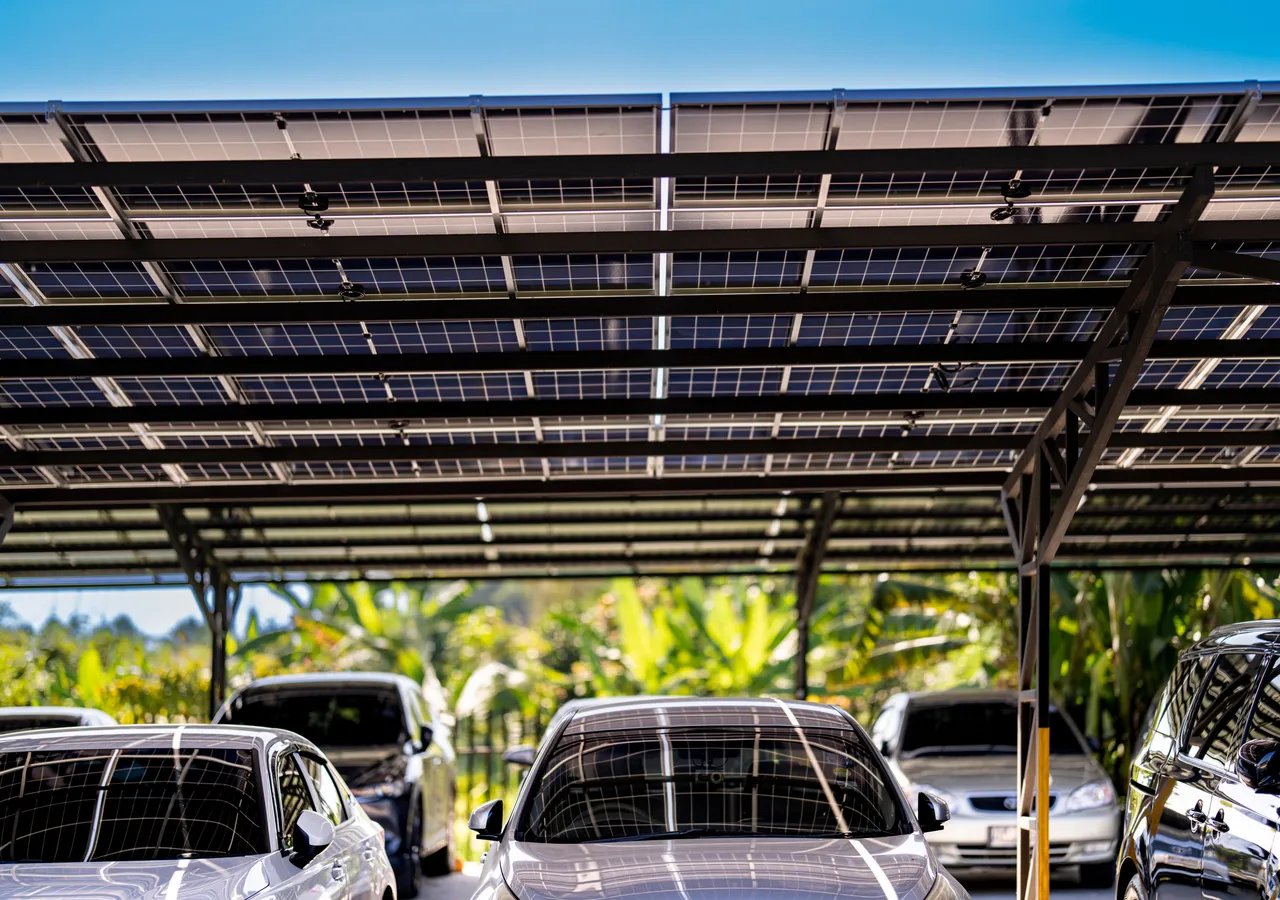 A carport roofed with solar panels shading parked cars beneath it.