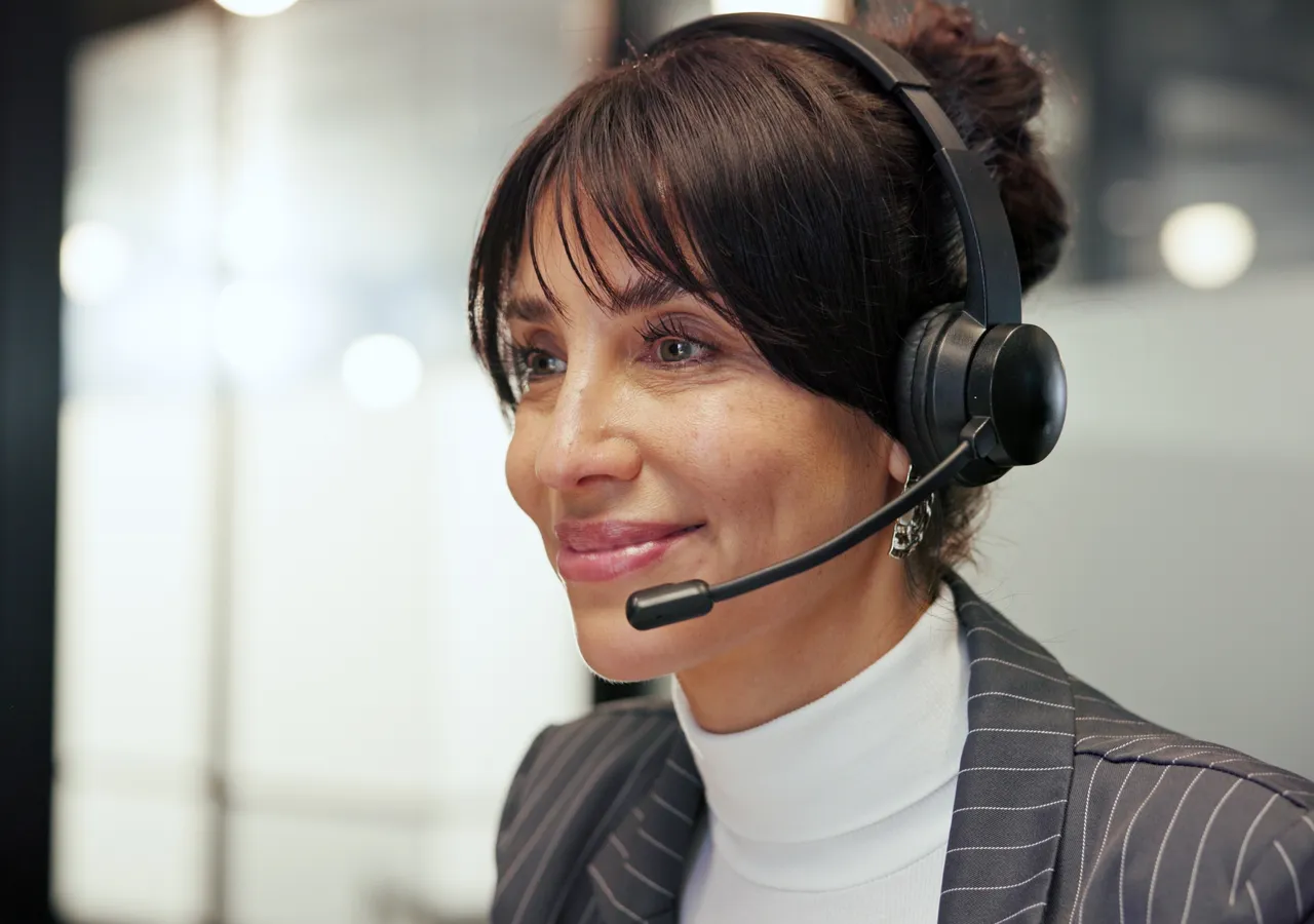 Close view of a support agent wearing a headset while working at a computer.