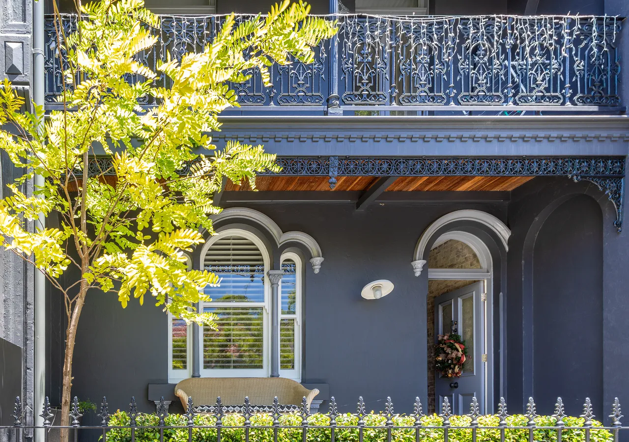 A heritage terrace house with an iron-lace balcony and tall arched windows.